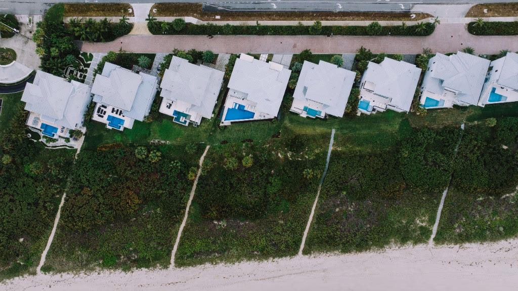 Vista aérea de alquileres frente al mar en el Sur de la Florida con piscinas, representando un portafolio de propiedades vacacionales y de largo plazo.